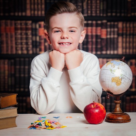 Fotoshooting Junge mit Apfel vor Büchern